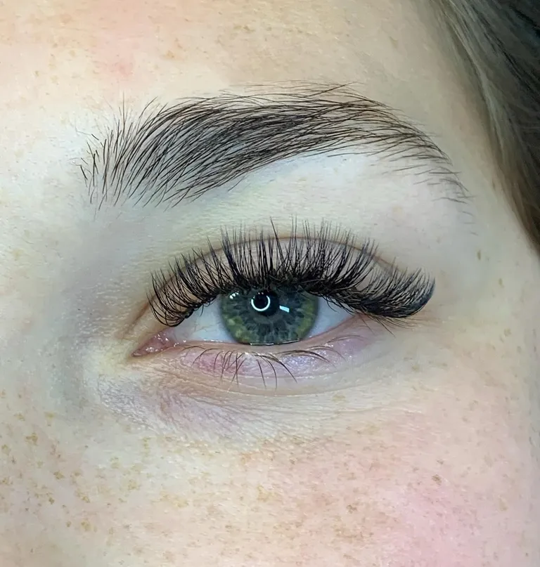 Close-up of a green eye with a wispy hybrid eyelash extension set blending textured spikes and soft volume by Made by Marissa.