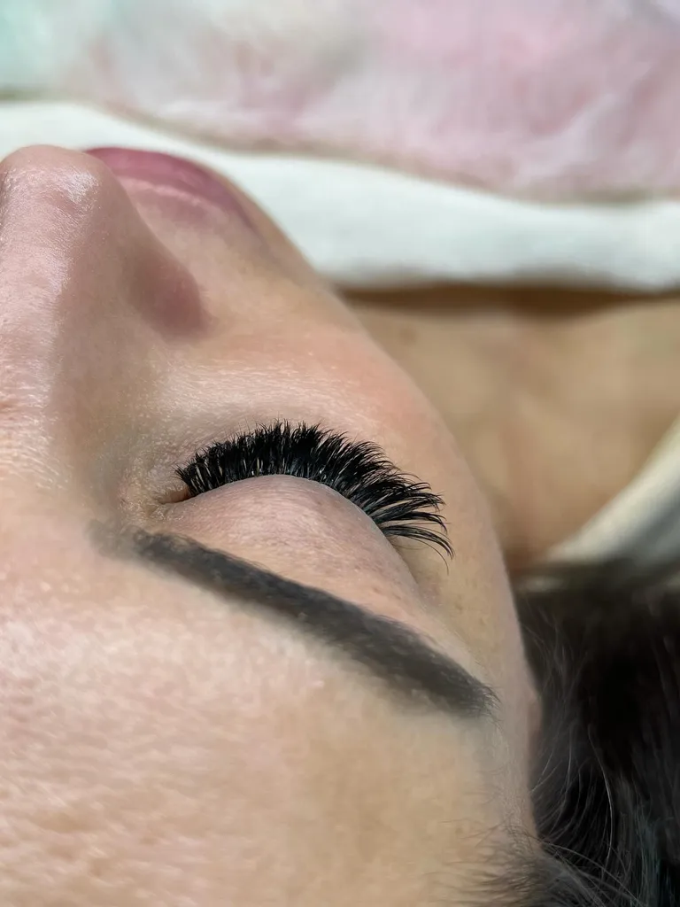 Side profile of a closed eye showing dense volume eyelash extensions with a dark, even lash line by Made by Marissa.