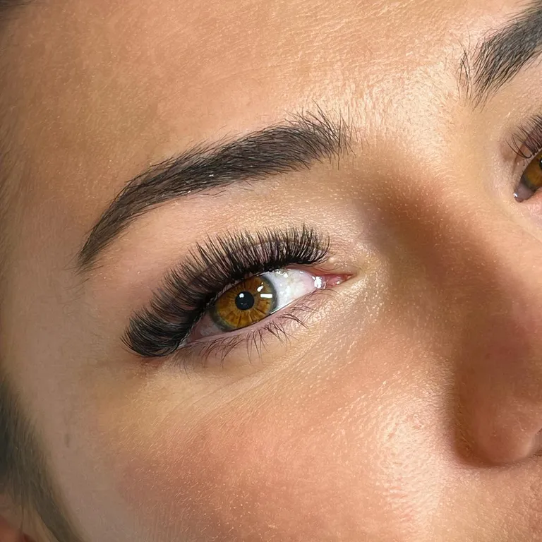 Close-up of an amber eye with a dramatic volume eyelash extension set and a dense elongated outer corner by Made by Marissa.