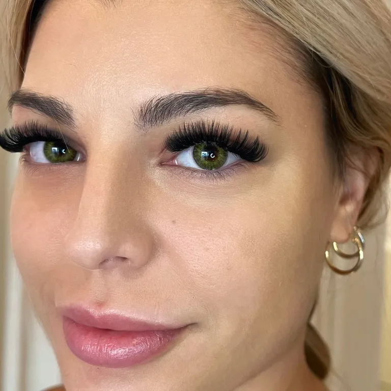 Portrait of a green-eyed client wearing a bold volume eyelash extension set with full fans and a lifted cat-eye finish by Made by Marissa.