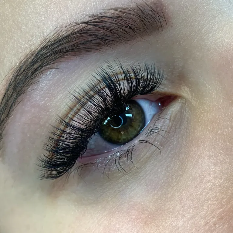 Close-up of a green eye with a textured volume eyelash extension set featuring airy spikes and layered fans by Made by Marissa.