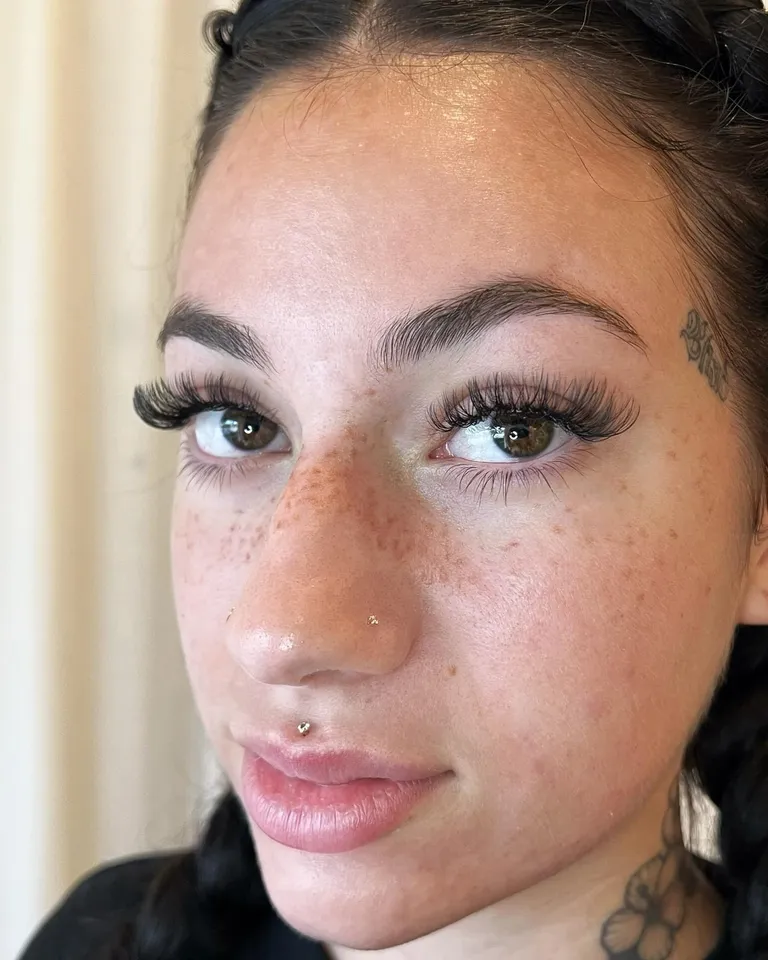 Portrait of a freckled client wearing long, airy volume eyelash extensions with a soft lifted shape by Made by Marissa.