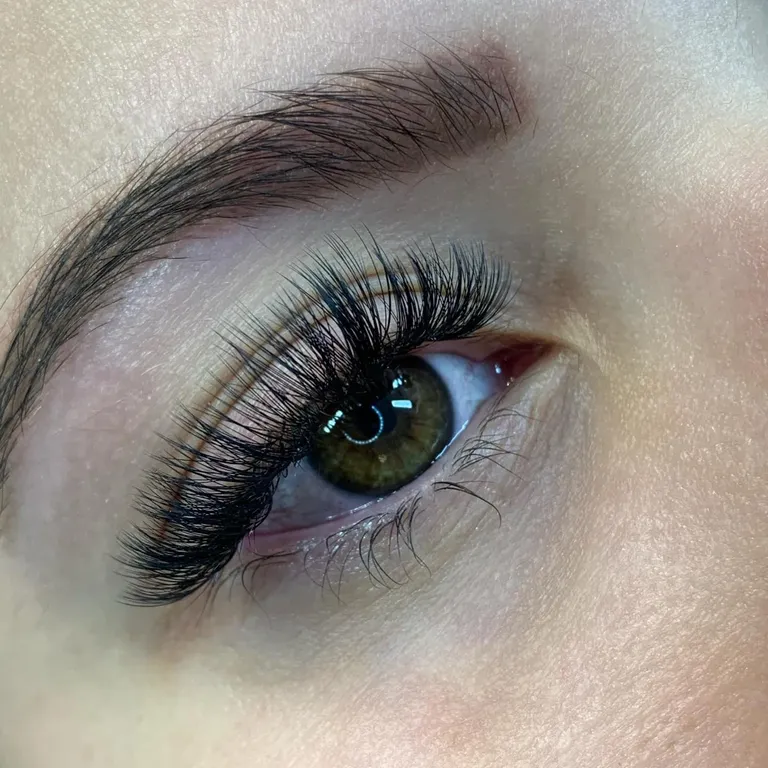 Detailed close-up of a green eye showing layered volume lash fans, fine spikes, and a dense base by Made by Marissa.