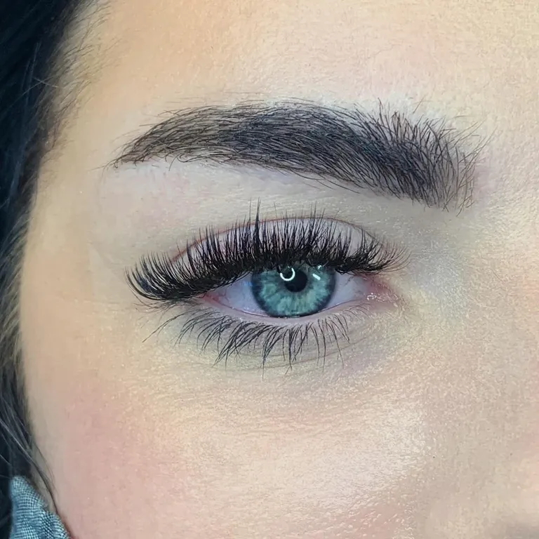 Close-up of a blue eye wearing a textured volume eyelash extension set with alternating wispy lengths by Made by Marissa.